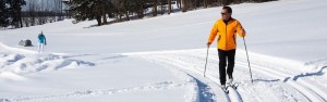 A couple cross-country skiing across a field